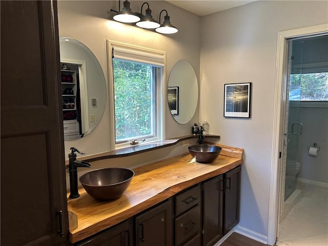 full bathroom with double vanity, toilet, baseboards, and a sink