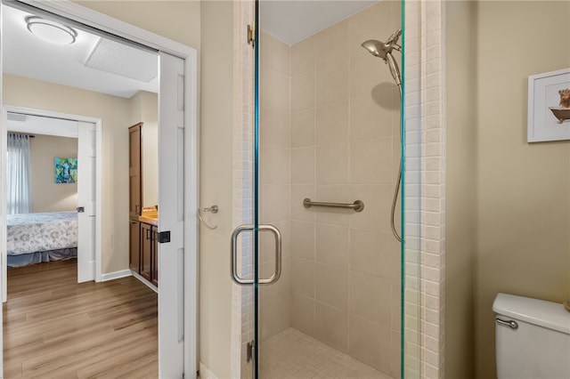 ensuite bathroom featuring wood finished floors, baseboards, ensuite bath, a shower stall, and toilet