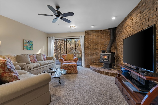 carpeted living area featuring a ceiling fan, brick wall, and a wood stove