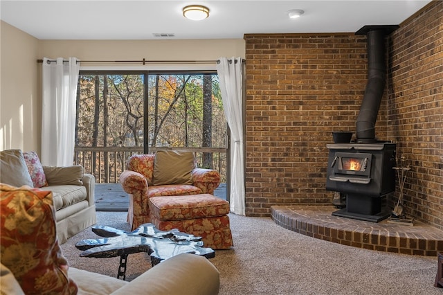 carpeted living room with visible vents, brick wall, and a wood stove