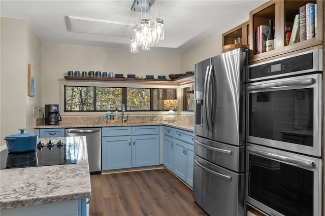 kitchen featuring blue cabinetry, a chandelier, dark wood-style floors, stainless steel appliances, and a sink