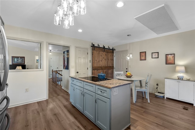 kitchen featuring a barn door, pendant lighting, black electric stovetop, and wood finished floors