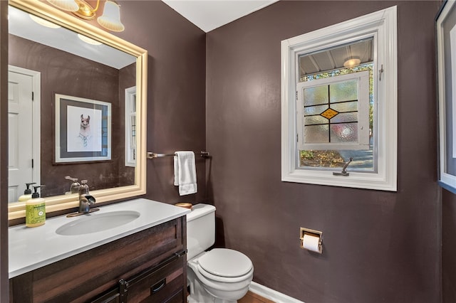 bathroom featuring toilet, vanity, and baseboards