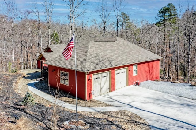 exterior space with a garage, a wooded view, and driveway