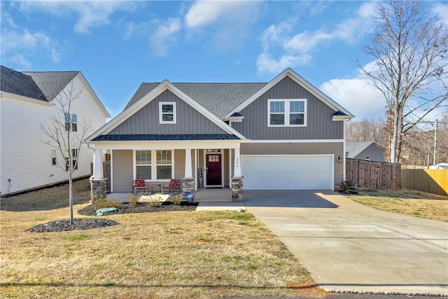 craftsman-style home with driveway, stone siding, fence, covered porch, and a garage