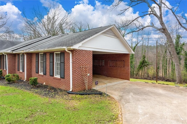 view of side of property featuring brick siding, an attached carport, and concrete driveway