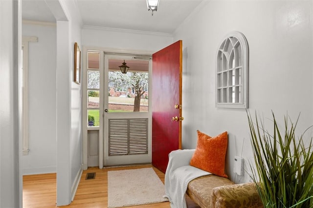 entryway featuring visible vents, light wood-style floors, and ornamental molding