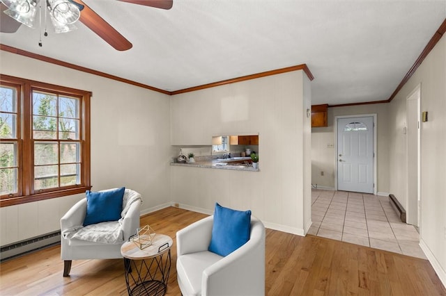 living area featuring a baseboard heating unit, light wood-style flooring, a wealth of natural light, and ceiling fan