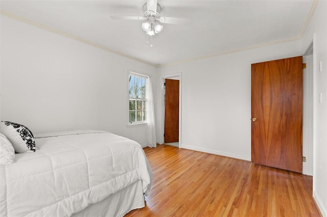 bedroom featuring ceiling fan, baseboards, light wood-style floors, and ornamental molding