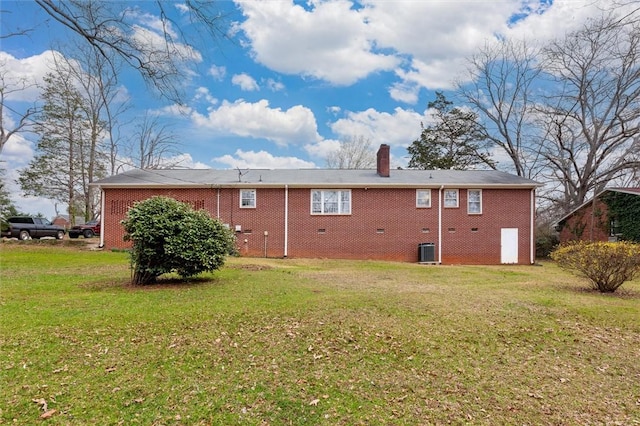 rear view of house with central air condition unit, a lawn, and a chimney