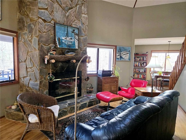 living area with a stone fireplace and wood finished floors