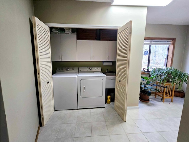 laundry area with cabinet space, separate washer and dryer, and light tile patterned flooring