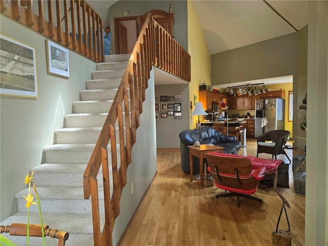 staircase with high vaulted ceiling and wood finished floors