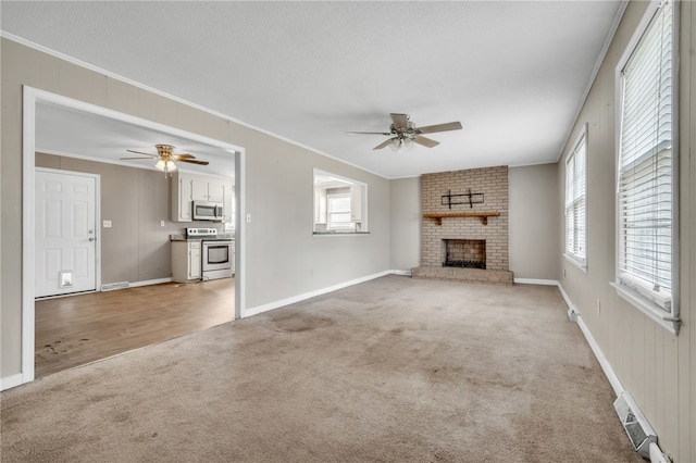 unfurnished living room featuring light colored carpet, crown molding, and ceiling fan