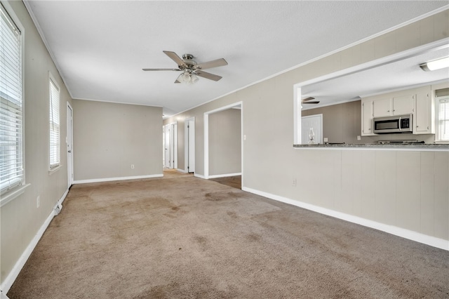 unfurnished living room featuring baseboards, light carpet, ceiling fan, and ornamental molding