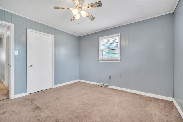 empty room with visible vents, carpet flooring, crown molding, and a ceiling fan