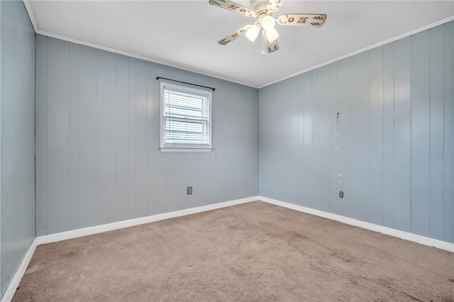 carpeted empty room featuring crown molding, baseboards, and ceiling fan