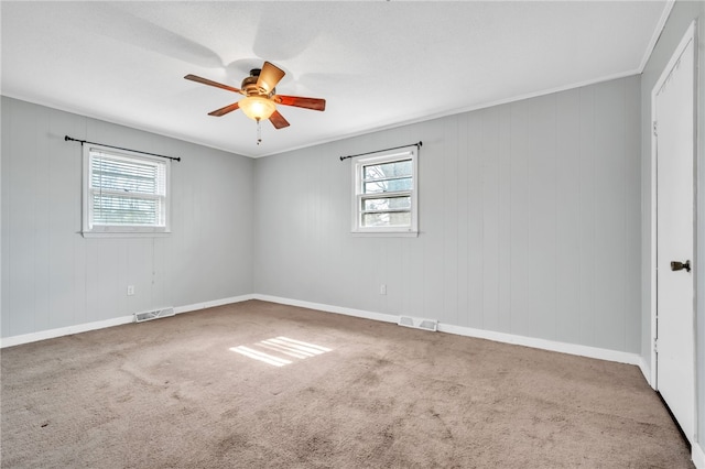 carpeted empty room featuring plenty of natural light, visible vents, and ceiling fan