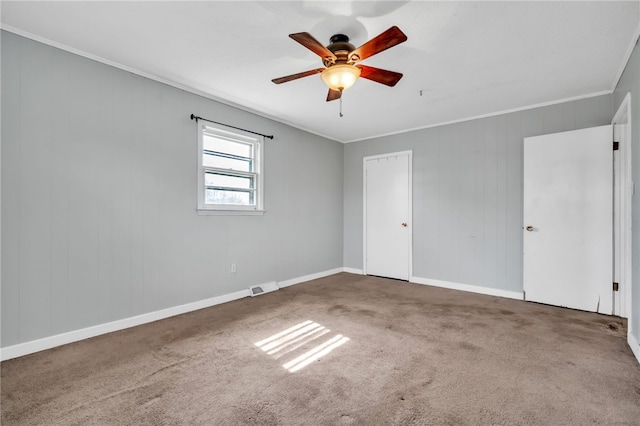 unfurnished bedroom featuring visible vents, carpet floors, ceiling fan, and crown molding