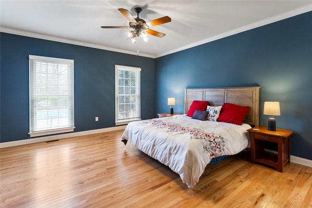 bedroom featuring visible vents, baseboards, ornamental molding, wood finished floors, and a ceiling fan