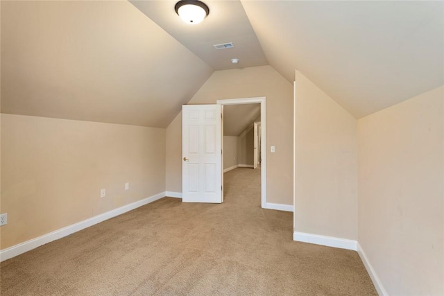 additional living space featuring visible vents, lofted ceiling, baseboards, and light carpet