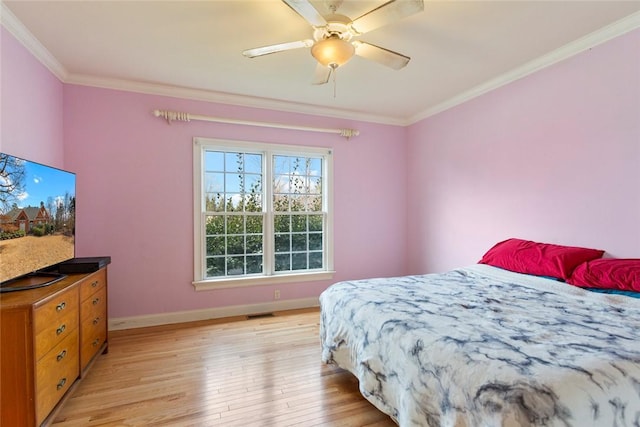 bedroom featuring visible vents, a ceiling fan, crown molding, light wood finished floors, and baseboards