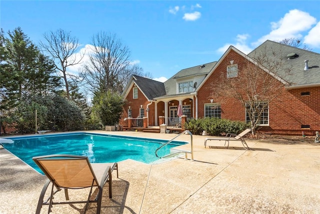 outdoor pool featuring a patio area and a diving board