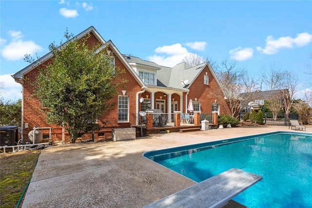 back of house featuring an outdoor pool, a patio, brick siding, and fence