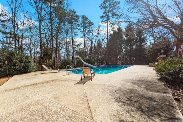 outdoor pool with a water slide and a patio