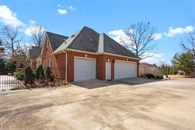 view of home's exterior with fence, concrete driveway, a shingled roof, a garage, and brick siding