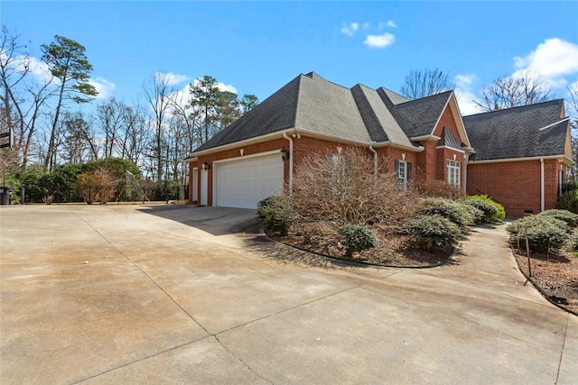 view of side of property featuring brick siding, roof with shingles, concrete driveway, and an attached garage