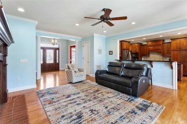 living room with baseboards, light wood-style floors, ornamental molding, and ornate columns