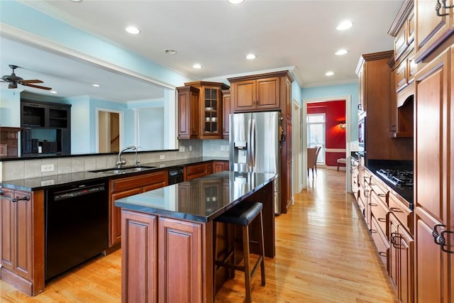 kitchen featuring black appliances, a breakfast bar, a sink, a center island, and brown cabinetry