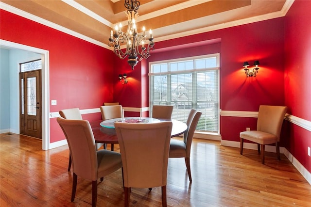 dining room featuring a tray ceiling, baseboards, an inviting chandelier, and wood finished floors