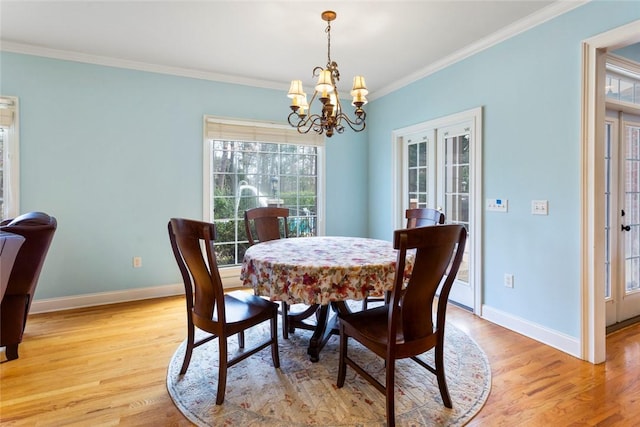 dining room featuring baseboards, an inviting chandelier, ornamental molding, and light wood finished floors