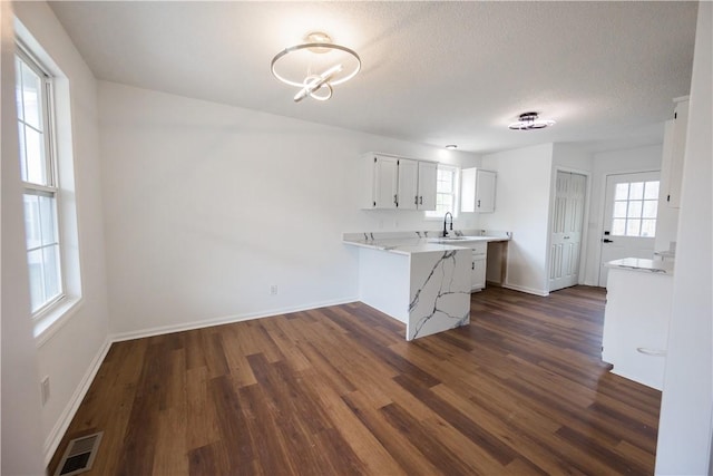 kitchen featuring visible vents, dark wood finished floors, light countertops, a peninsula, and white cabinets