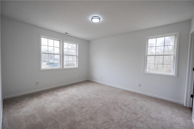 empty room with baseboards, carpet, visible vents, and a textured ceiling