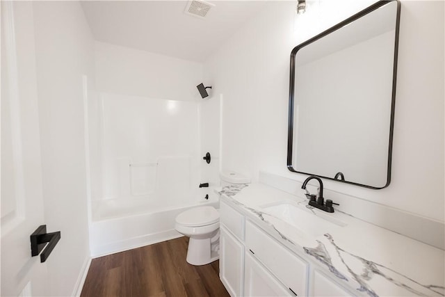 bathroom featuring vanity, wood finished floors, visible vents, shower / bathing tub combination, and toilet