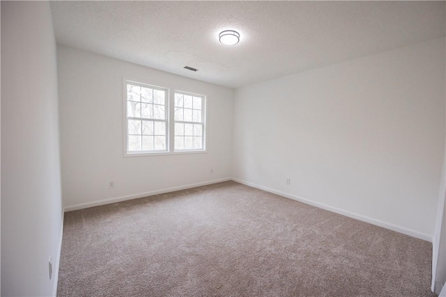 carpeted spare room featuring visible vents, baseboards, and a textured ceiling