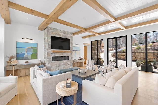 living area with beamed ceiling, wood finished floors, and a fireplace