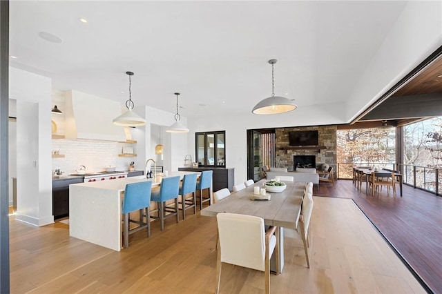 dining space featuring light wood-style flooring, recessed lighting, and a fireplace