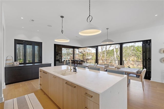 kitchen featuring light wood-type flooring, modern cabinets, light brown cabinets, a sink, and light countertops