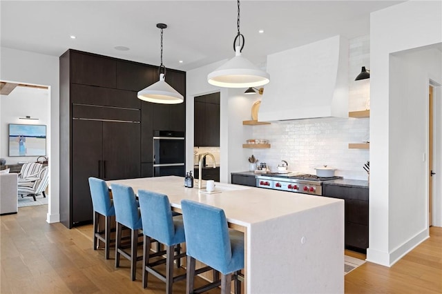 kitchen with light wood finished floors, open shelves, a breakfast bar, modern cabinets, and a sink