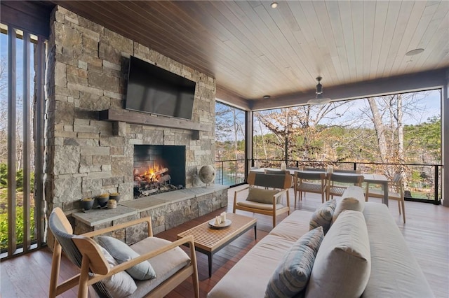 sunroom featuring wood ceiling and an outdoor stone fireplace