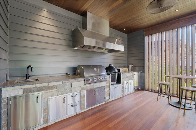 kitchen with fridge, wall chimney exhaust hood, wooden ceiling, and a sink