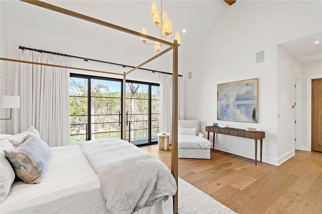 bedroom with a notable chandelier, baseboards, light wood finished floors, and high vaulted ceiling