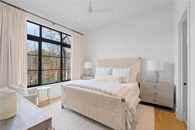 bedroom featuring a ceiling fan, multiple windows, light wood-style floors, and baseboards