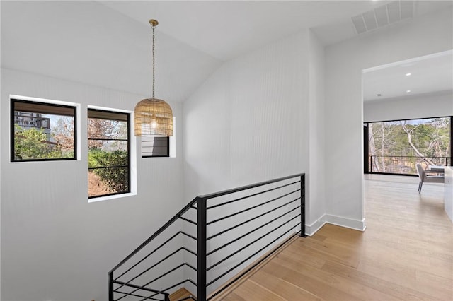 staircase with visible vents, lofted ceiling, and wood finished floors