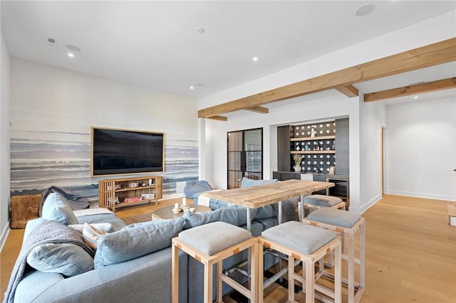 living area featuring light wood-type flooring, beamed ceiling, recessed lighting, a bar, and baseboards