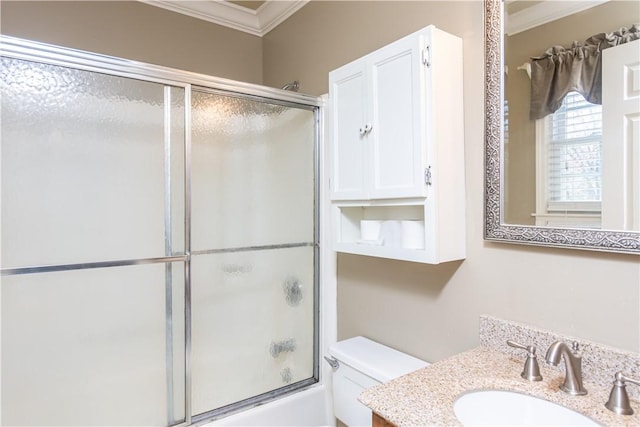 bathroom with vanity, crown molding, toilet, and bath / shower combo with glass door